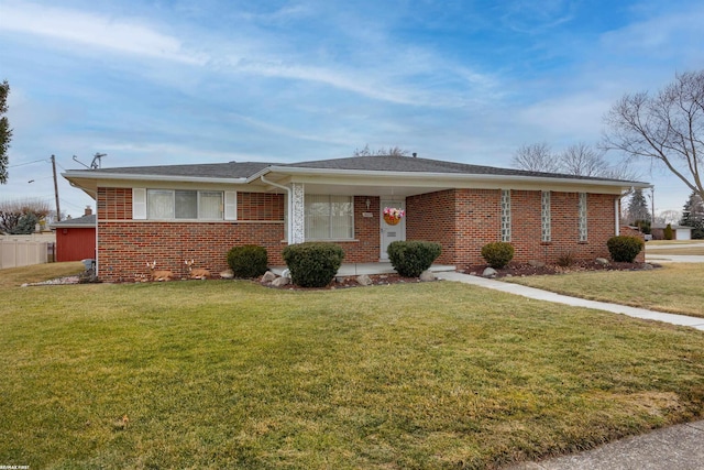 view of front of property featuring a front yard, fence, and brick siding