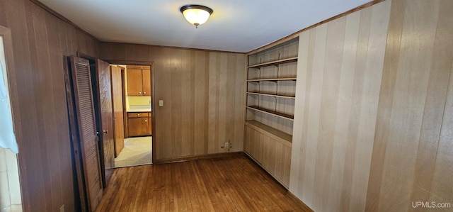 hall with dark wood finished floors, built in features, and wooden walls