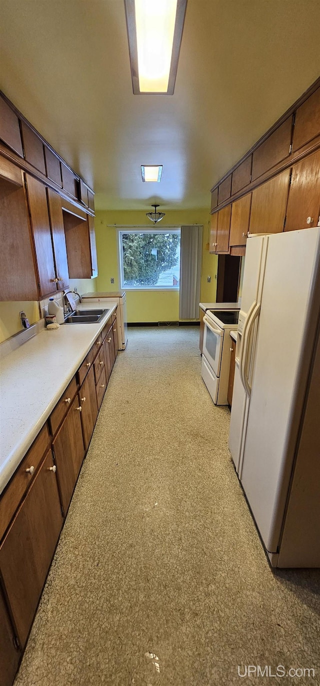 kitchen with light countertops, white appliances, a sink, and brown cabinets