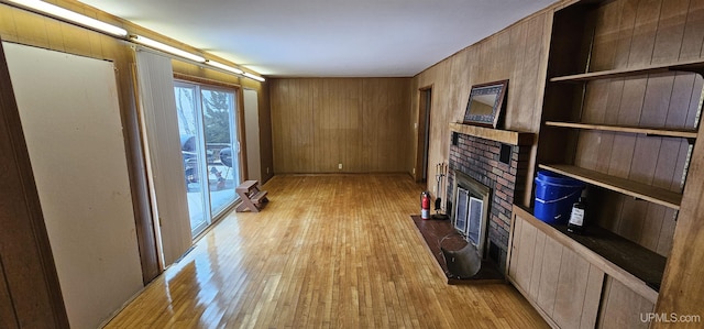 living room featuring wood walls, a fireplace, and light wood-style flooring