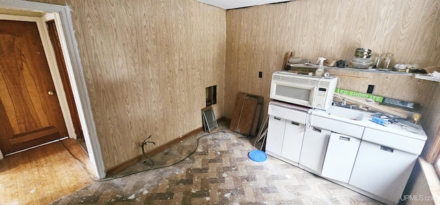 kitchen with white microwave, white cabinetry, light countertops, and a sink