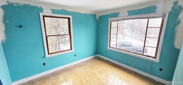 spare room featuring plenty of natural light, baseboards, and wood finished floors