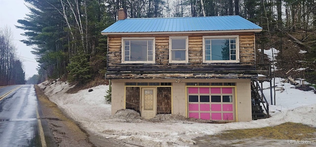 view of front of property with metal roof, a chimney, and an attached garage