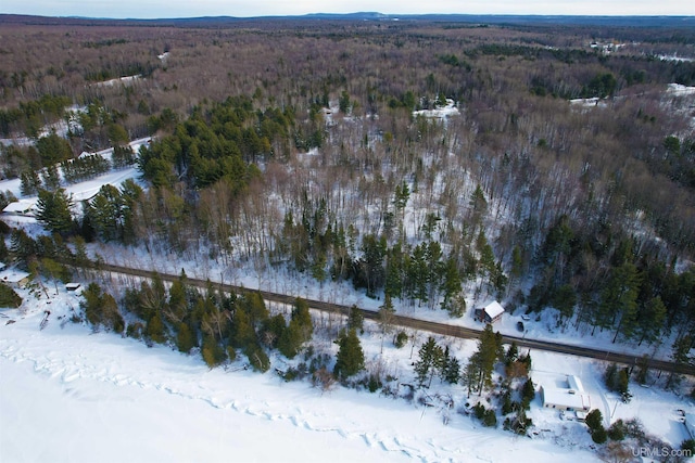 snowy aerial view featuring a wooded view