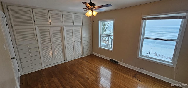 unfurnished bedroom featuring baseboards, visible vents, ceiling fan, dark wood-style flooring, and a closet