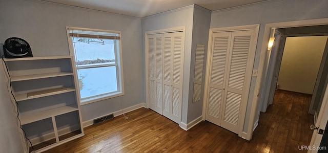 unfurnished bedroom with hardwood / wood-style flooring, multiple windows, and visible vents