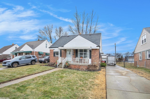 bungalow with brick siding, a porch, a front yard, and fence