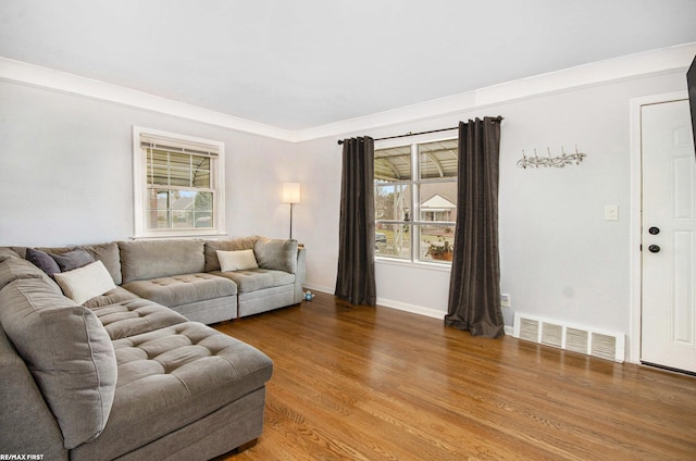 living room with a wealth of natural light, visible vents, baseboards, and wood finished floors