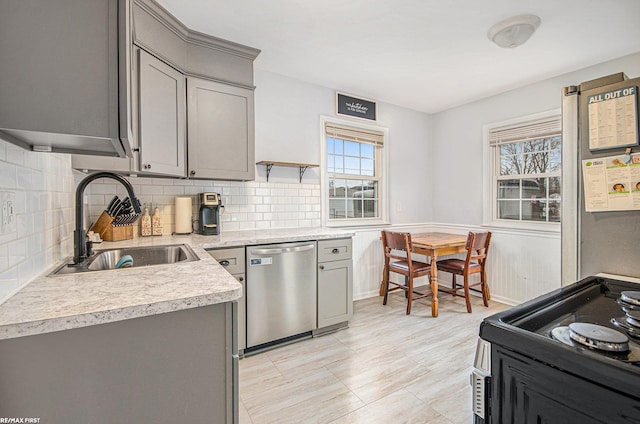 kitchen with a sink, gray cabinets, dishwasher, and light countertops