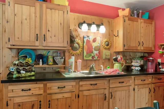 kitchen with tasteful backsplash, dark countertops, a sink, and light brown cabinetry