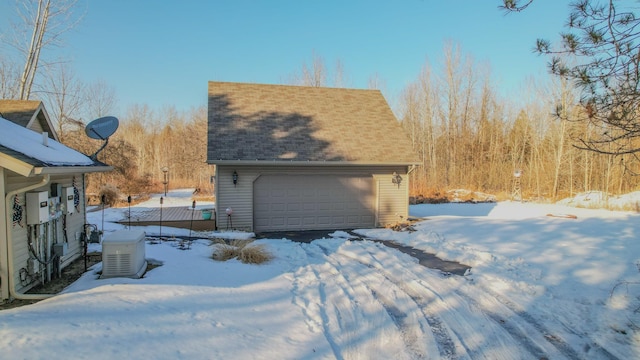 view of snow covered exterior with a garage and an outdoor structure