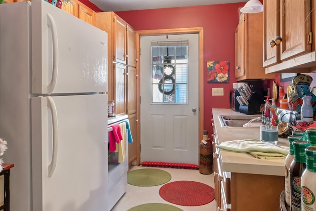 kitchen with brown cabinetry, light countertops, range with electric cooktop, and freestanding refrigerator