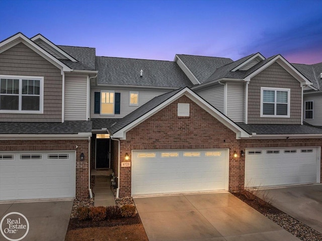 multi unit property featuring a garage, concrete driveway, brick siding, and a shingled roof