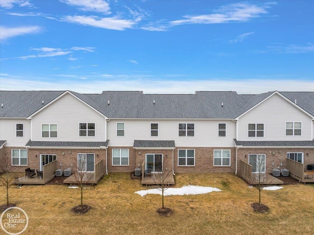 back of property featuring a lawn, a deck, central AC, and brick siding