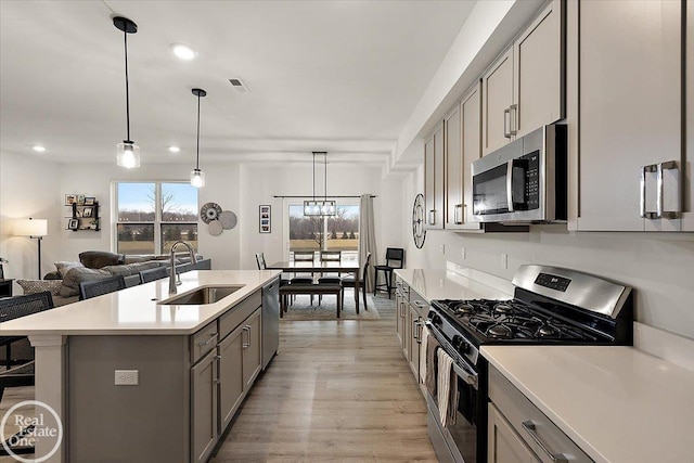 kitchen with light wood-style flooring, light countertops, stainless steel appliances, gray cabinetry, and a sink