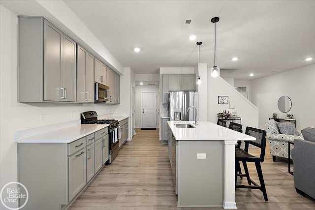 kitchen with stainless steel appliances, light wood-style floors, a sink, and gray cabinetry