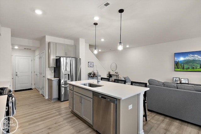 kitchen with light wood finished floors, gray cabinets, visible vents, appliances with stainless steel finishes, and a sink