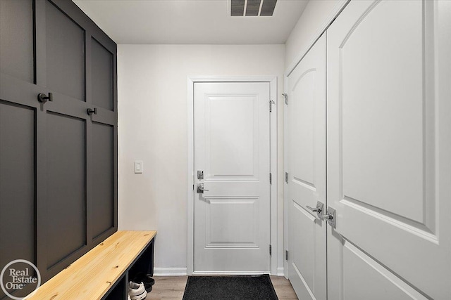 mudroom with light wood finished floors, baseboards, and visible vents