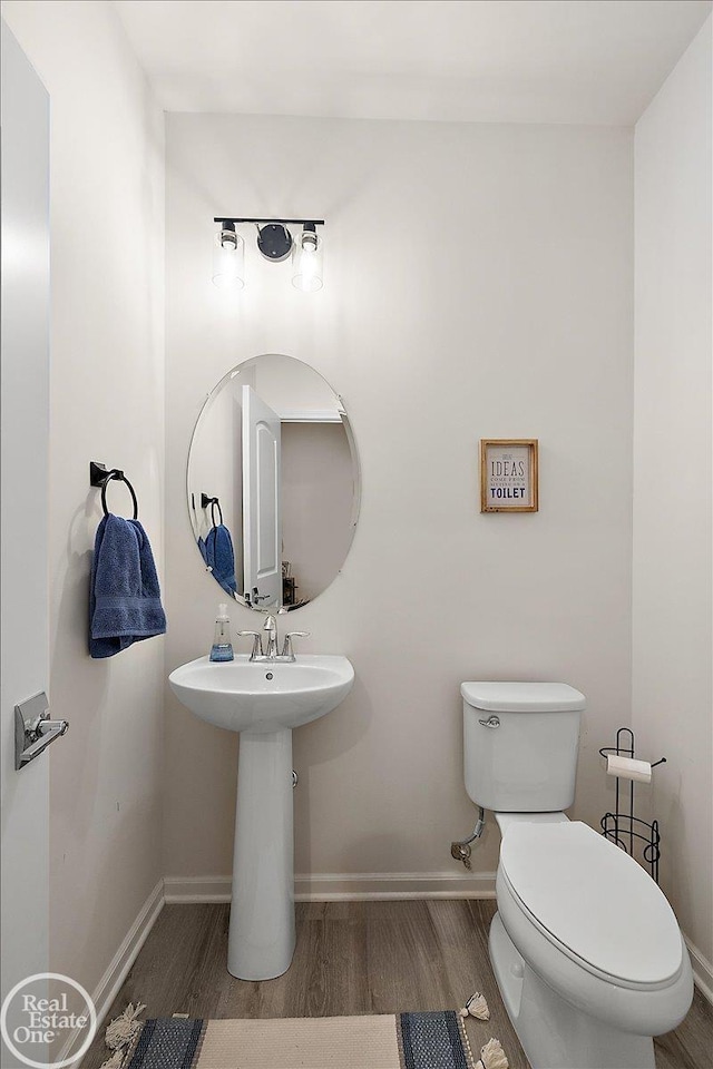 bathroom with wood finished floors, toilet, and baseboards