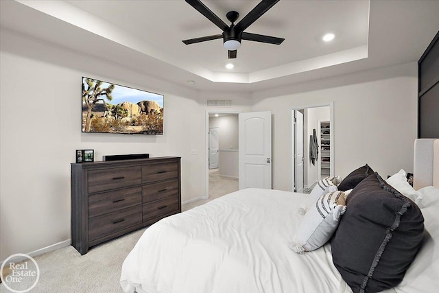 bedroom with light carpet, recessed lighting, a raised ceiling, and baseboards