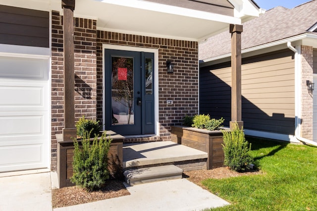 view of exterior entry with an attached garage and brick siding