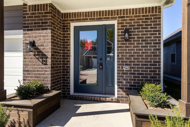 property entrance with a garage and brick siding