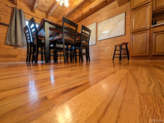 unfurnished dining area featuring lofted ceiling with beams, wood walls, wood ceiling, and hardwood / wood-style flooring