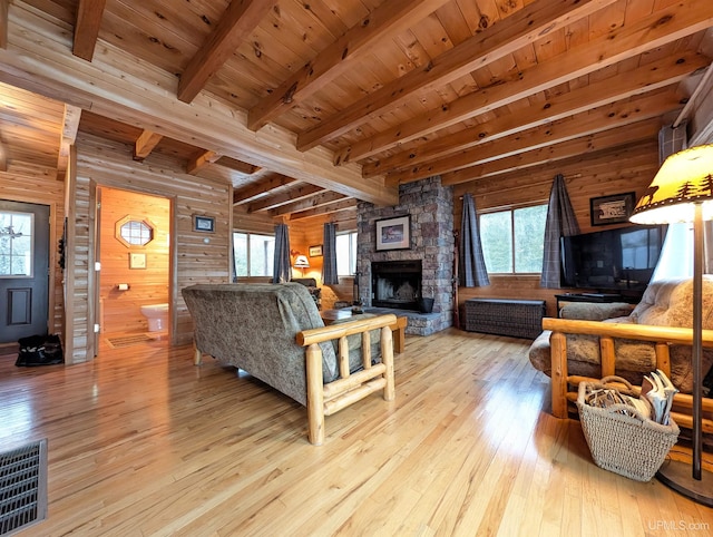 living area with wood ceiling, wooden walls, hardwood / wood-style floors, and a stone fireplace