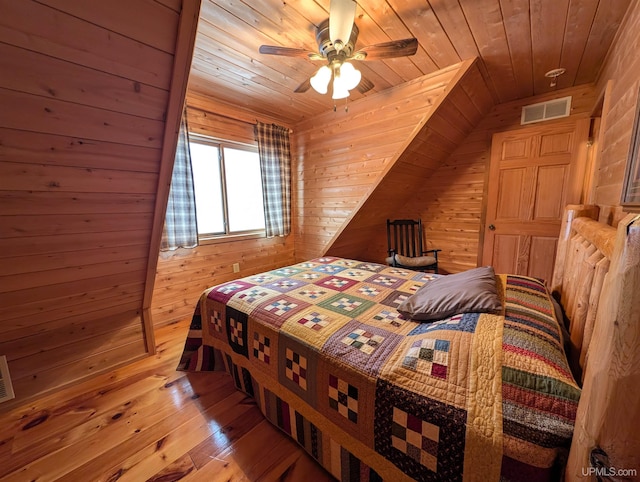 bedroom with wood ceiling, wood walls, wood-type flooring, and visible vents