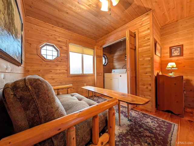 sitting room with a ceiling fan, washing machine and dryer, wood ceiling, wood walls, and wood finished floors