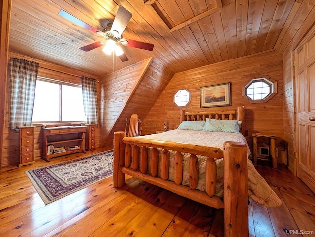 bedroom with a ceiling fan, wooden ceiling, hardwood / wood-style floors, vaulted ceiling, and wood walls