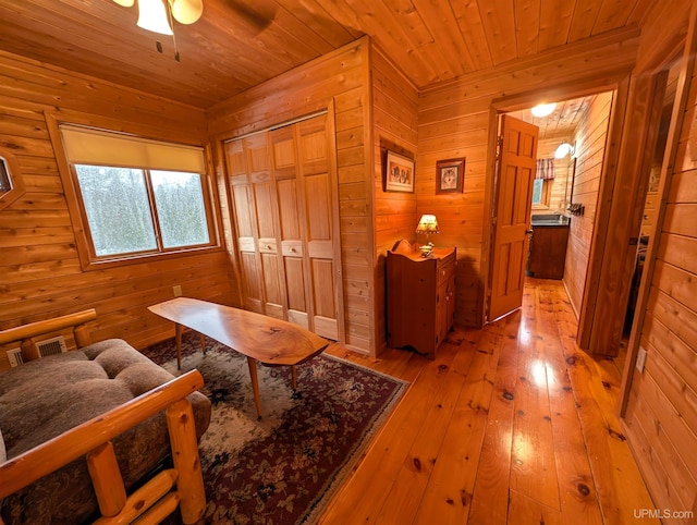 interior space with wooden ceiling, wooden walls, visible vents, and hardwood / wood-style flooring