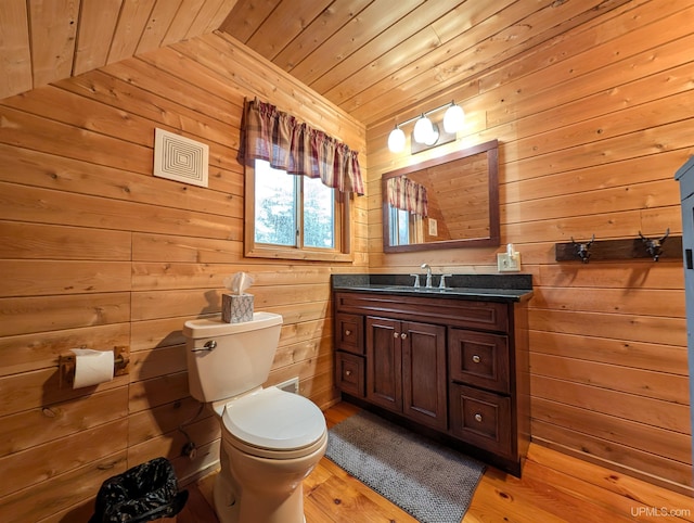 bathroom with toilet, wood walls, wood finished floors, wood ceiling, and vanity