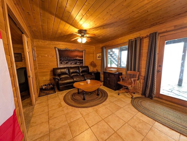 living area with wooden ceiling, wooden walls, light tile patterned floors, and a ceiling fan