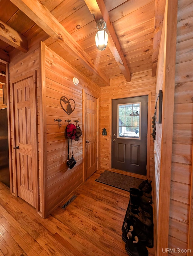 foyer featuring beam ceiling, visible vents, wood ceiling, wood walls, and wood finished floors