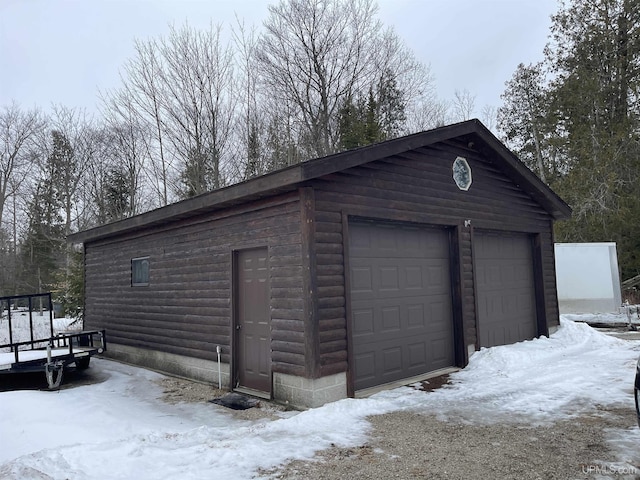 snow covered garage featuring a detached garage