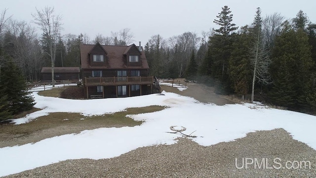 snow covered rear of property featuring a deck and a view of trees