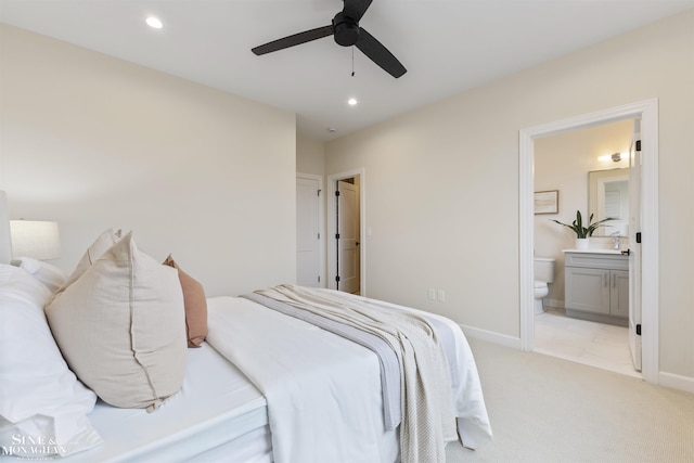 bedroom with recessed lighting, light colored carpet, ensuite bath, and baseboards