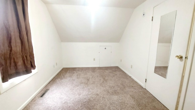 additional living space featuring carpet, visible vents, vaulted ceiling, and baseboards