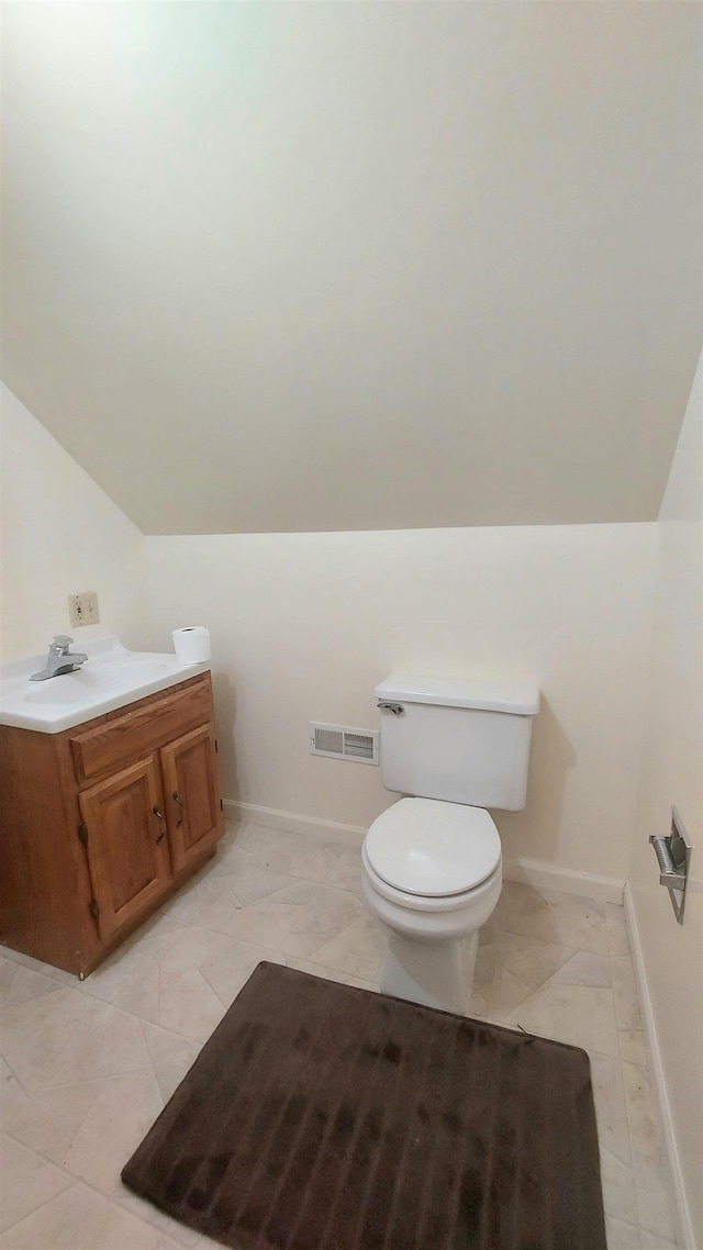 half bathroom featuring lofted ceiling, visible vents, toilet, vanity, and baseboards