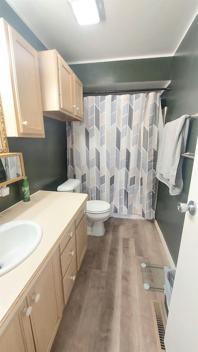 full bathroom with curtained shower, toilet, wood finished floors, vanity, and visible vents