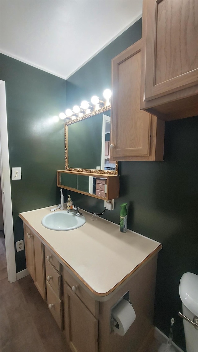 half bath with toilet, vanity, and baseboards