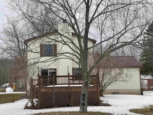 snow covered back of property featuring a deck