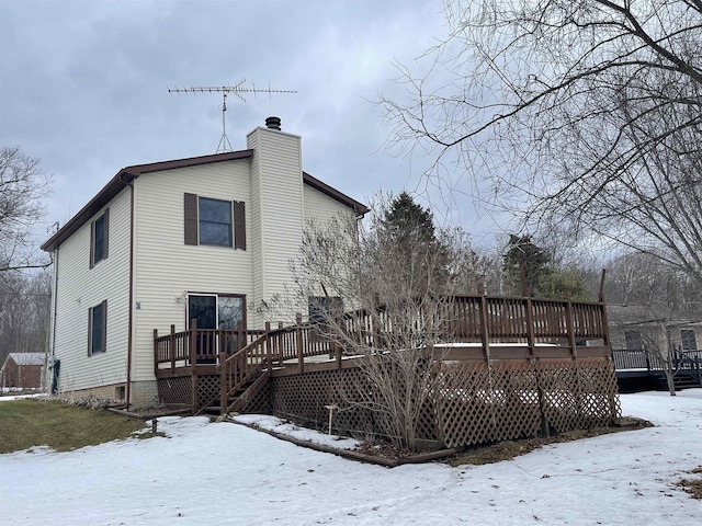 snow covered property featuring a chimney and a wooden deck