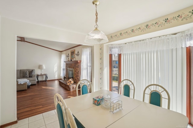 dining space with a fireplace, baseboards, crown molding, and light tile patterned flooring