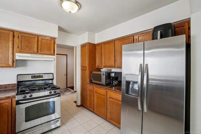 kitchen featuring appliances with stainless steel finishes, light tile patterned flooring, brown cabinets, and under cabinet range hood