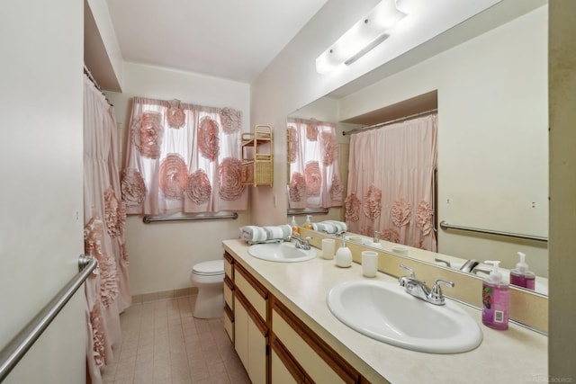 bathroom with baseboards, a sink, toilet, and double vanity