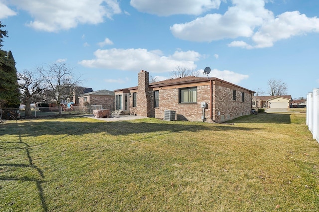 rear view of house with a yard, brick siding, a fenced backyard, and central air condition unit