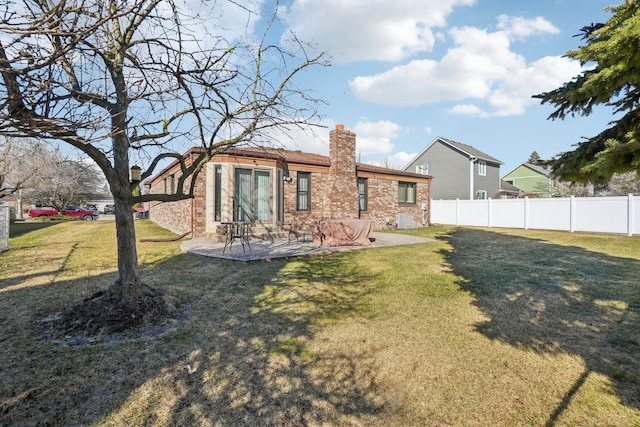 back of house with a lawn, a patio, a chimney, and fence