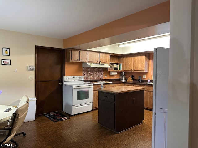 kitchen featuring white appliances, dark countertops, dark floors, a center island, and under cabinet range hood